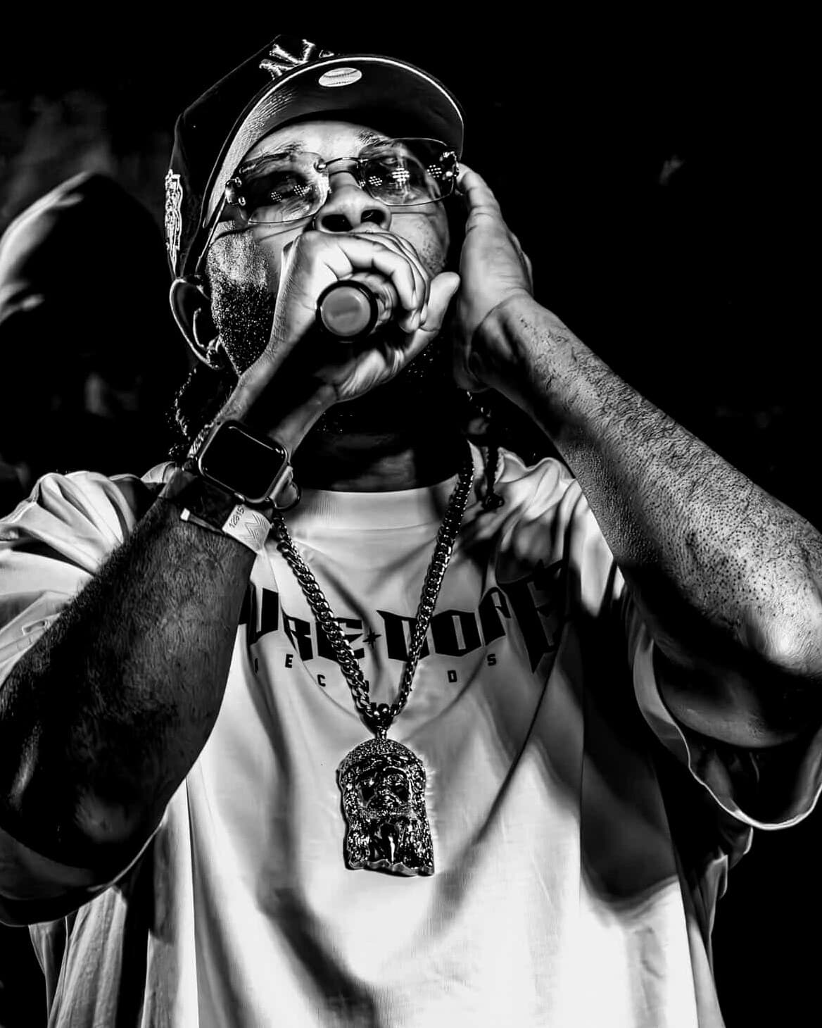 P.GUTTER performing, mic to his mouth, his other hand cupped to his ear, in a Pure Dope Records tee